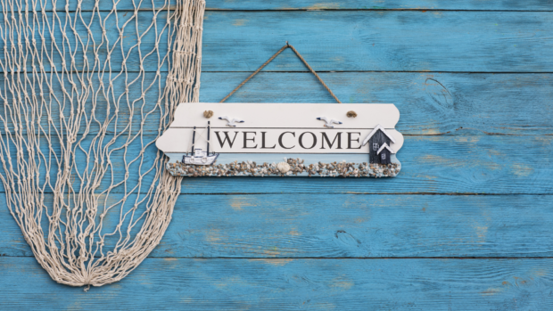 A welcome sign on a blue wooden background with fishing net