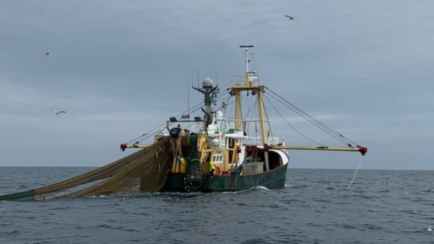 A fishing boat with a net cast into the water.