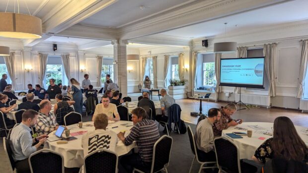 An expansive room with numerous people gathered at tables, interacting and sharing ideas.