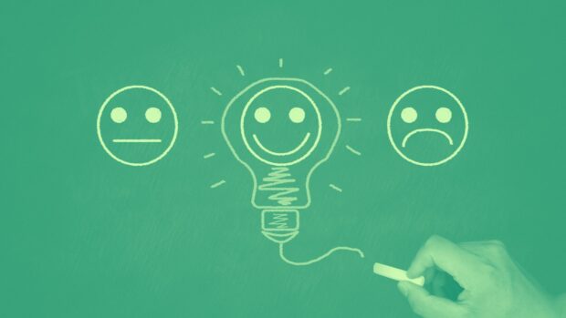A hand draws a light bulb with smiley faces, conveying a sense of joy and inspiration in creativity.